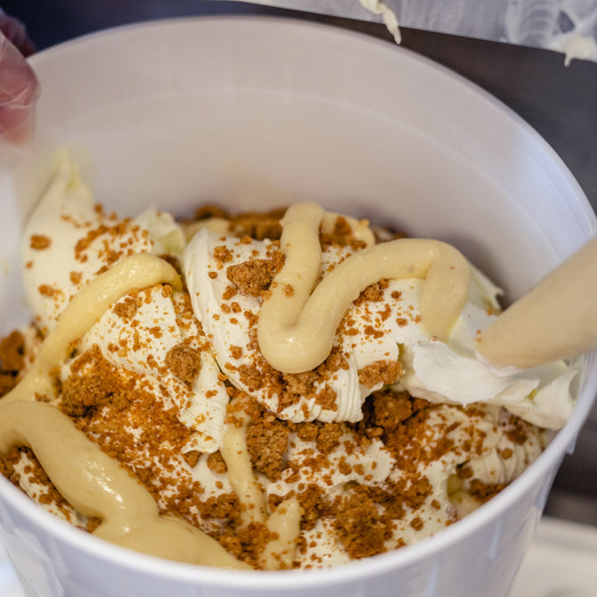 Close-up of a dessert with whipped cream and chocolate shavings in a white bowl.